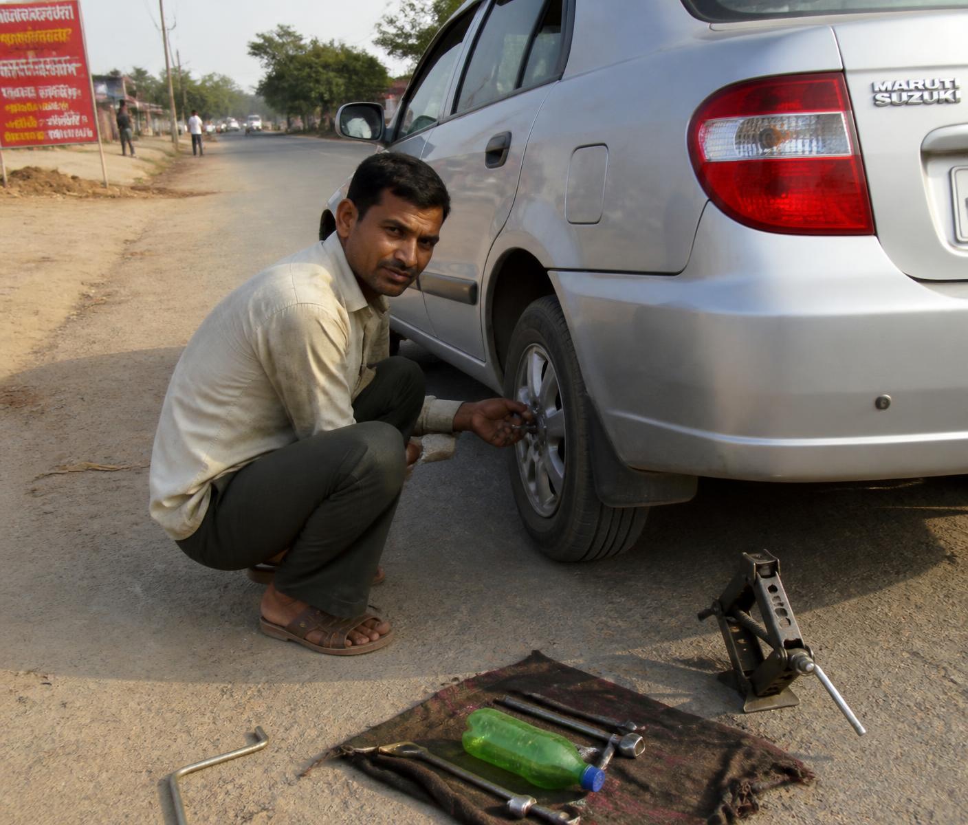 Technician repairing a car tyre at the roadside in India
